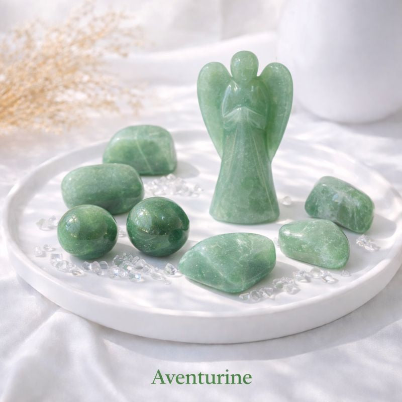 Green aventurine crystals and an angel carving on a white background in natural light.