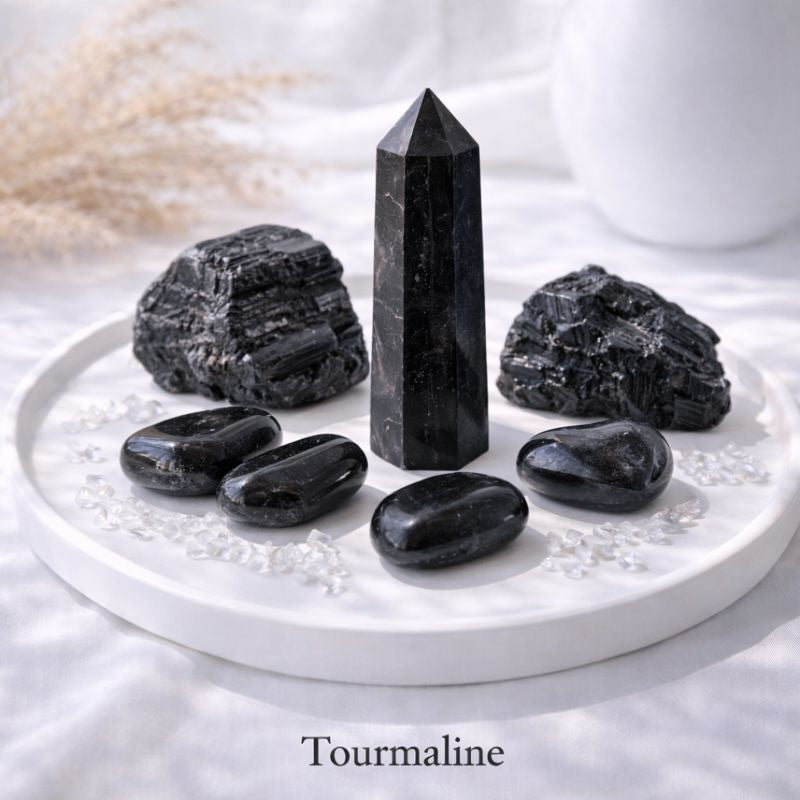 Black tourmaline crystal pillar standing upright on a bright white surface, illuminated by soft natural light, highlighting its raw texture and grounding presence